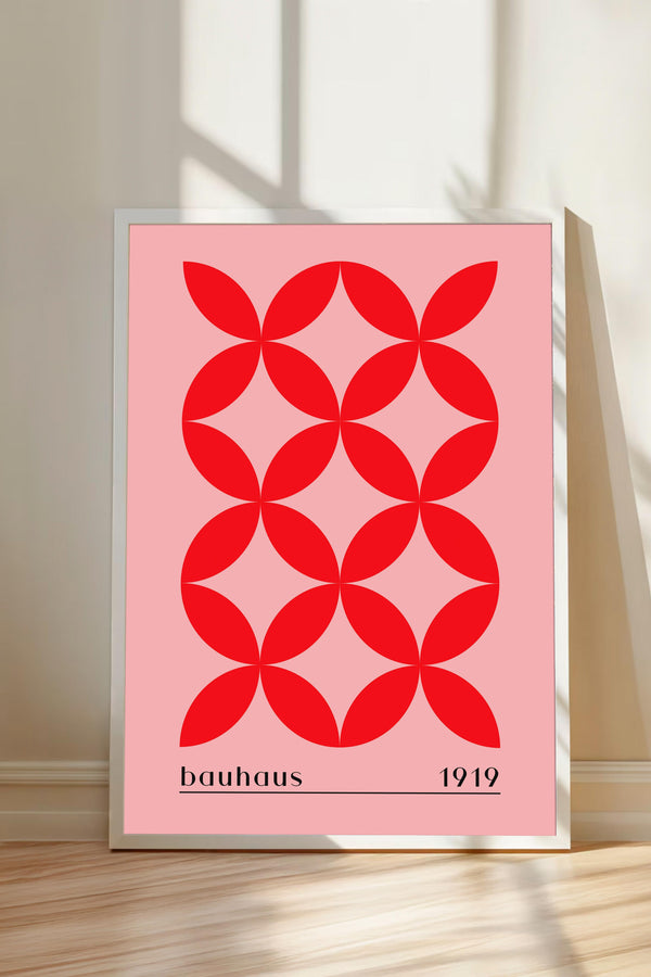 A framed poster with a geometric design of red circles on a pink background, representing the Bauhaus design school founded by Walter Gropius in 1919.