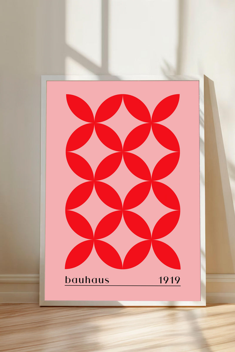 A framed poster with a geometric design of red circles on a pink background, representing the Bauhaus design school founded by Walter Gropius in 1919.