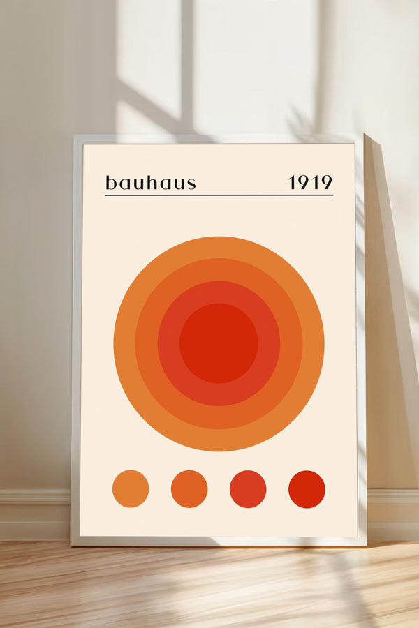A framed poster with a large circular design in shades of orange and red, along with the text "bauhaus 1919" displayed on it.
