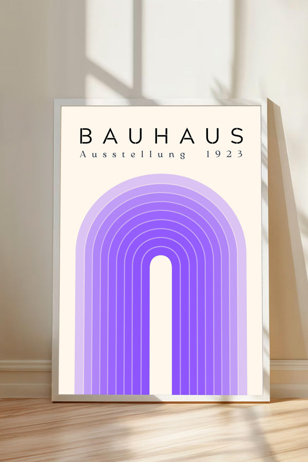 a poster or artwork with the text "BAHAU" and "AUSTELLLANG 1923" displayed prominently. The poster is framed and placed on a wooden floor, with a shadow cast on the wall behind it.