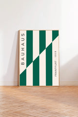 a minimalist poster with a bold geometric design, standing upright on a wooden floor against a white wall.