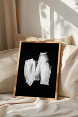 a black and white abstract painting displayed on a bed with a wooden frame.