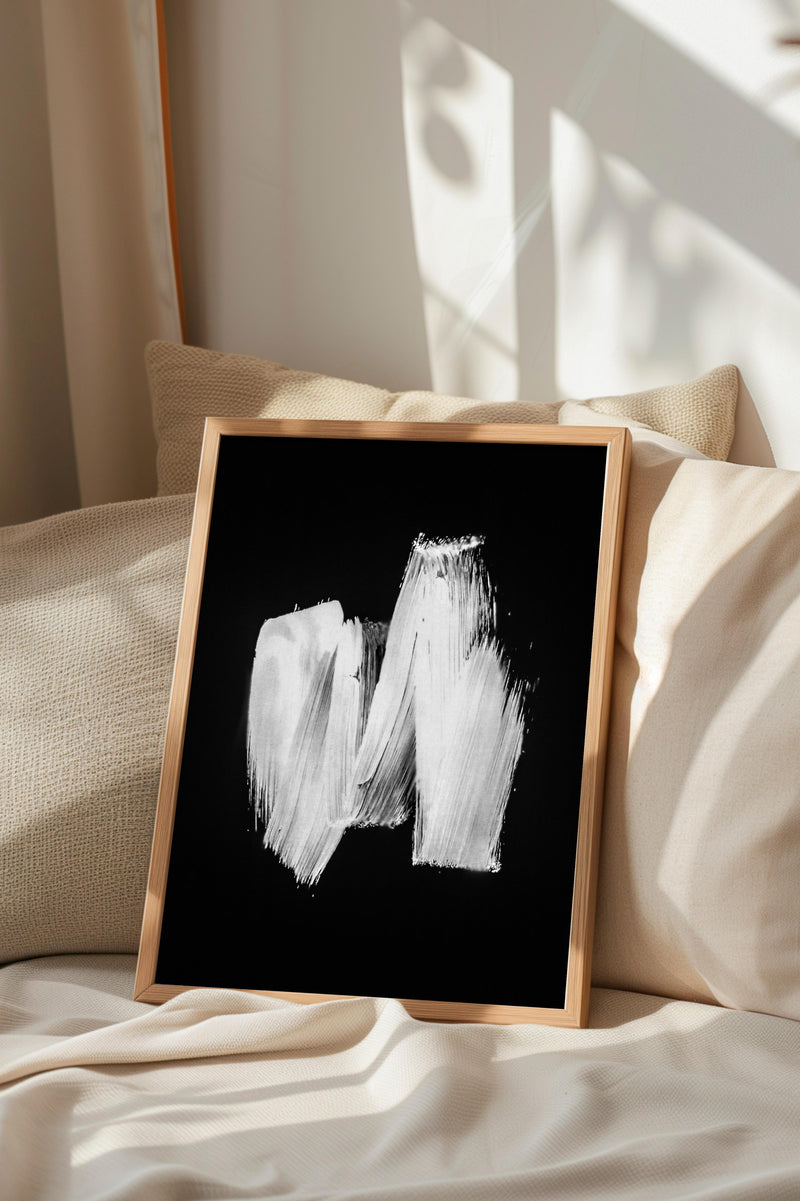a black and white abstract painting displayed on a bed with a wooden frame.