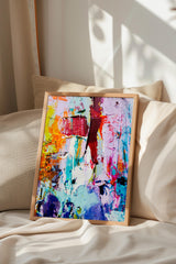 a vibrant, abstract painting with a mix of bold colors and dynamic brushstrokes, displayed on a bed with a beige pillow.
