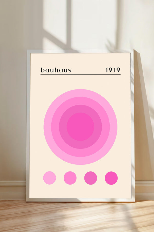 A framed poster with a minimalist design featuring a large pink circle and four smaller circles below it, along with the text "bauhaus 1919".