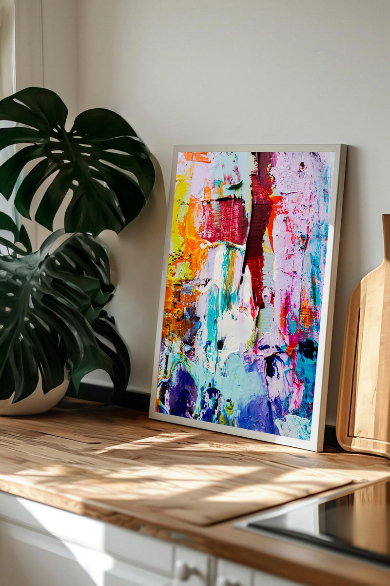 a vibrant, abstract painting displayed on a wooden surface, with a large monstera plant in the background.