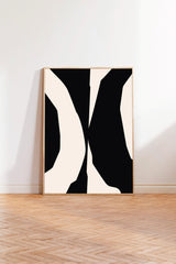 a large black and white abstract artwork displayed on a white wall in a room with a wooden floor.