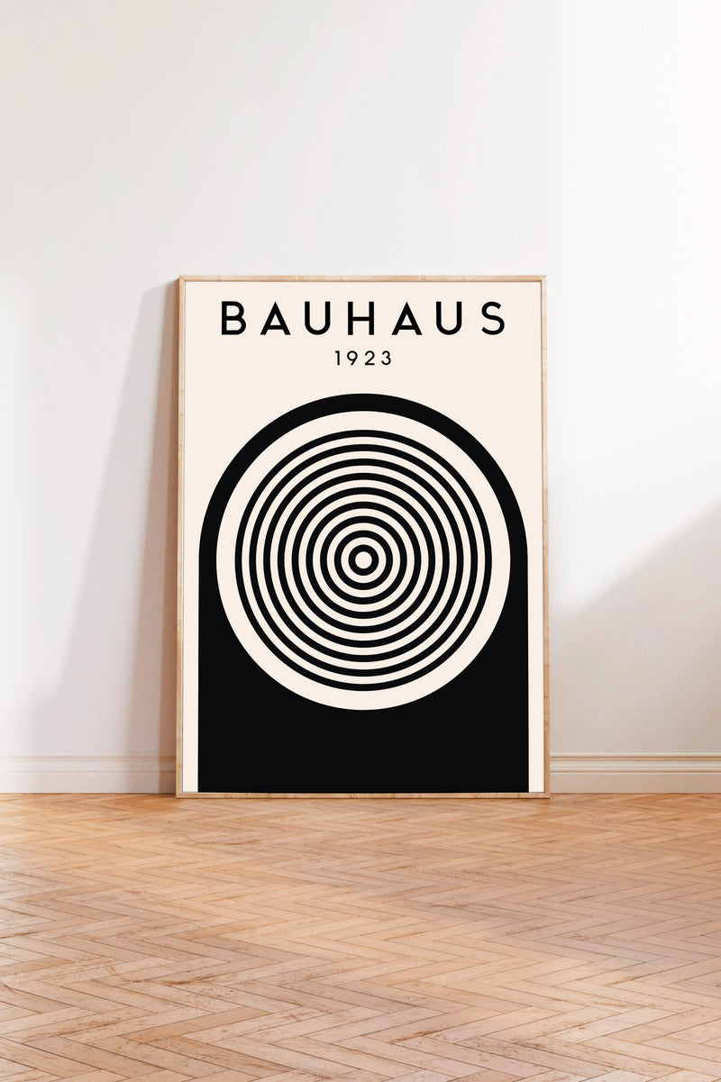 A poster of Bauhaus, a famous art school founded by Walter Gropius in 1923, is displayed on a white wall in a room with a wooden floor.