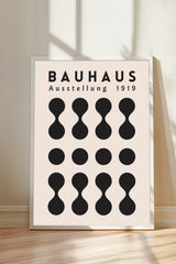 a poster or artwork with the text "BAHAUX" and "AUSTELLLUNG 1919" prominently displayed. The poster is framed and placed on a wooden floor, with a shadow cast on the wall behind it.