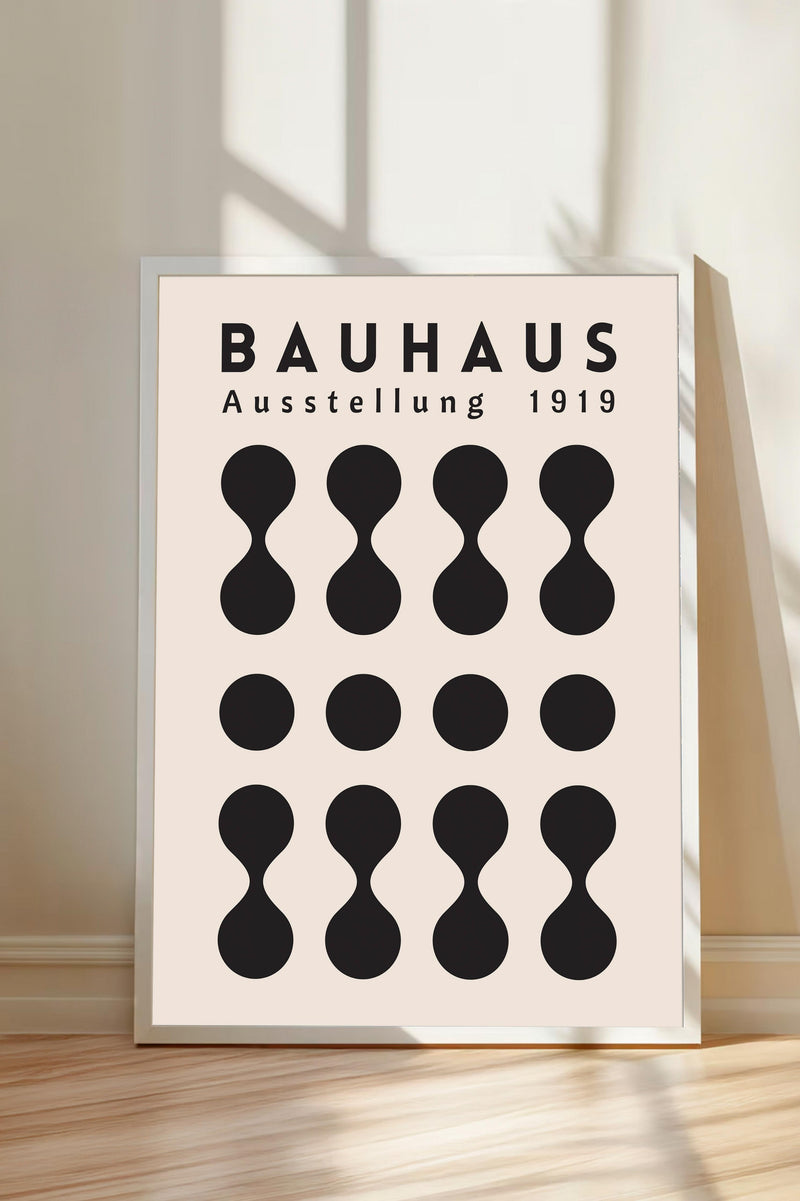 a poster or artwork with the text "BAHAUX" and "AUSTELLLUNG 1919" prominently displayed. The poster is framed and placed on a wooden floor, with a shadow cast on the wall behind it.