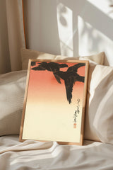 a framed artwork depicting a black bird in flight, with a warm orange and yellow gradient background.