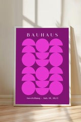 a poster with a geometric design in shades of pink and purple, displaying the name "BAHAU" and the date "July 19, 1923" at the bottom.
