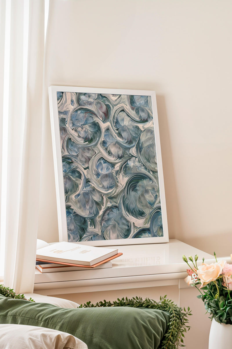 a white bookshelf with a framed abstract painting hanging on it. On the bookshelf, there is a stack of books and a vase of flowers.