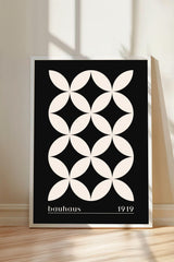A framed poster with a black and white geometric design featuring a repeating pattern of circles and lines.