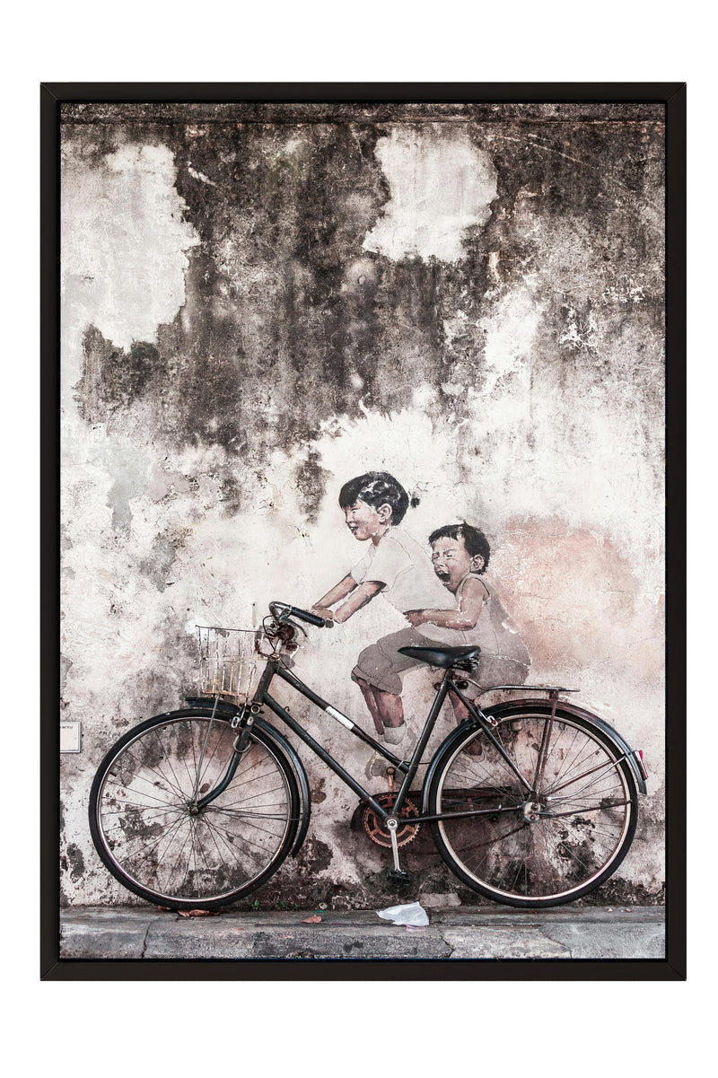 two children riding a bicycle on a wall.