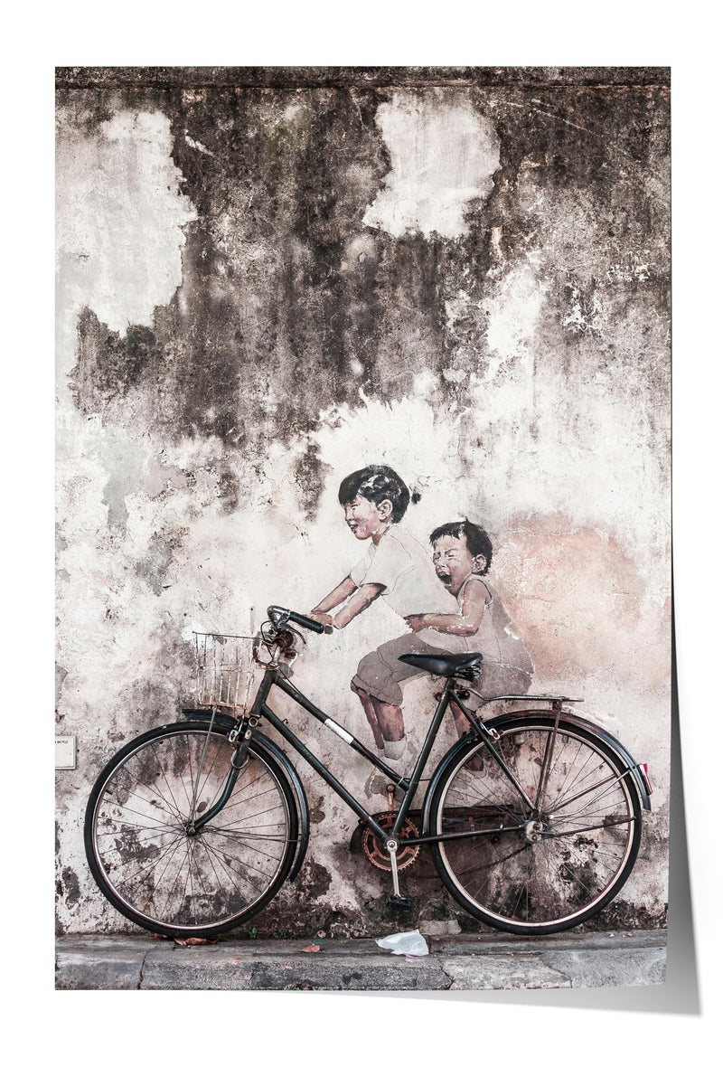 A black bicycle is parked in front of a weathered concrete wall, with two figures depicted on the wall, one of whom is riding the bicycle.