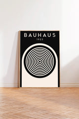 A black and white poster of the Bauhaus school of design, featuring a large circular design with concentric circles on a white background.
